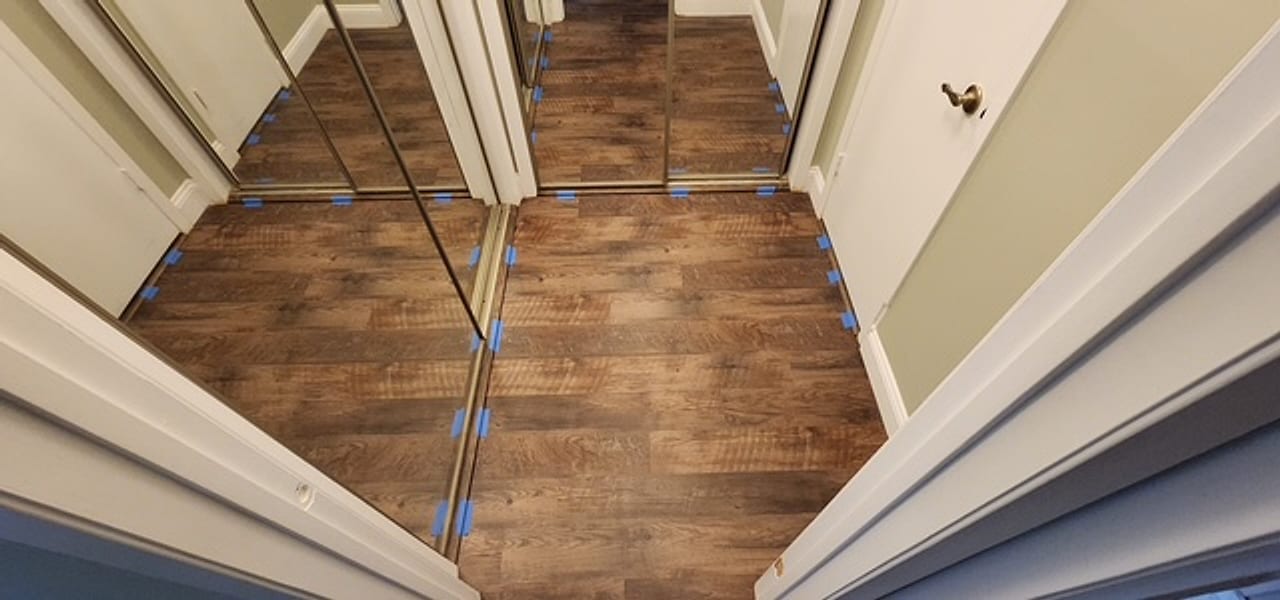 New plank flooring running into mirrored closets, expansion spacers still set, by Frankie D’s Flooring