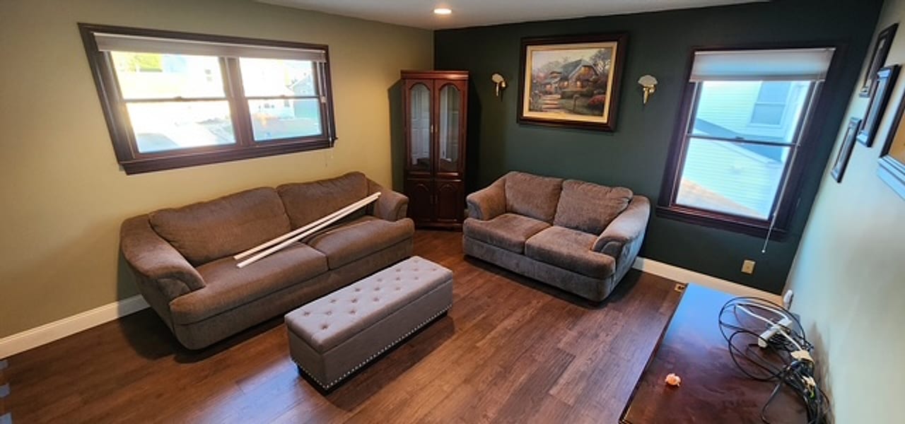 Wide dark plank flooring installed in a living room with a green accent wall by Frankie D’s Flooring