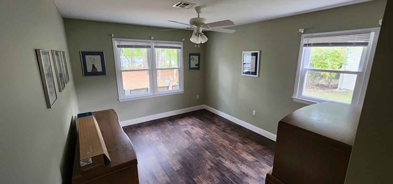 Hand-scraped dark plank flooring in a sage-green bedroom by Frankie D’s Flooring
